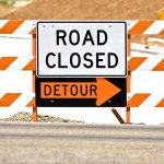 A road closed sign with a detour arrow pointing right