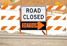 A road closed sign with a detour arrow pointing right